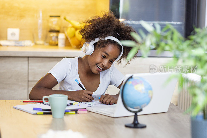 Preteen schoolgirl doing her homework with digital tablet at home.